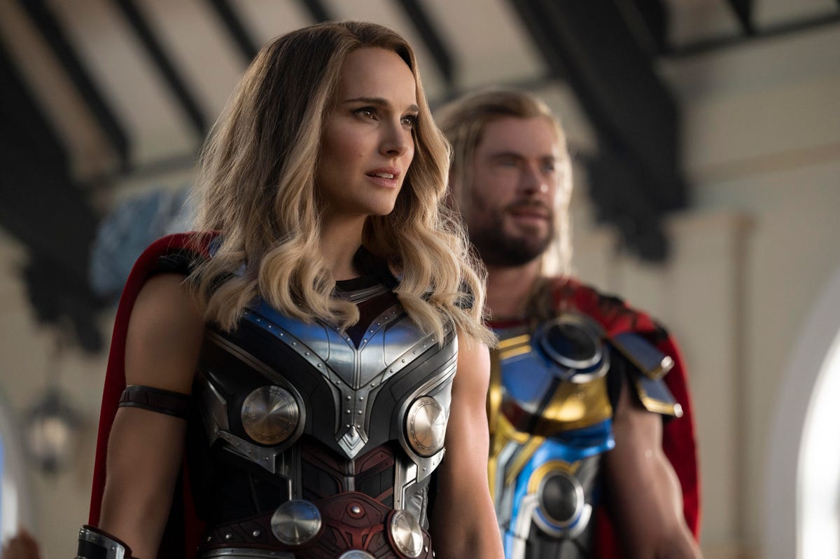 Jane Foster stands in the foreground and Thor is in the background of Thor: Love and Thunder.