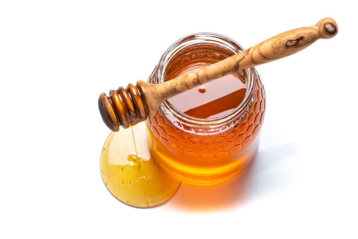 Jar of honey and honey dipper shot from above on a white background