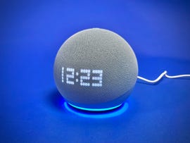The 5th-gen Amazon Echo Dot with Clock sitting against a blue background. The pixelated clockface displays the time, 12:23.