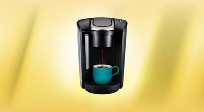 A black Keurig K-Select coffee brewer against a yellow background.