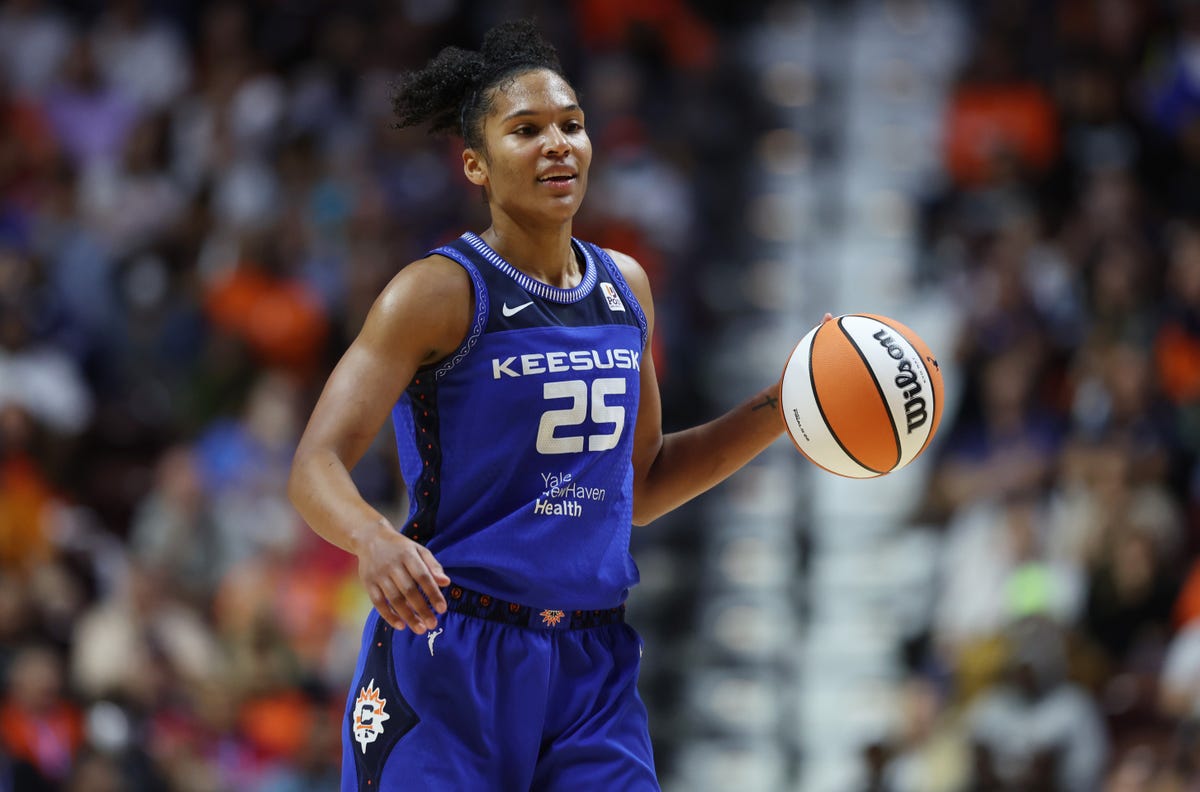 Alyssa Thomas of the Connecticut Sun smiles as she dribbles the orange-and-white WNBA basketball.