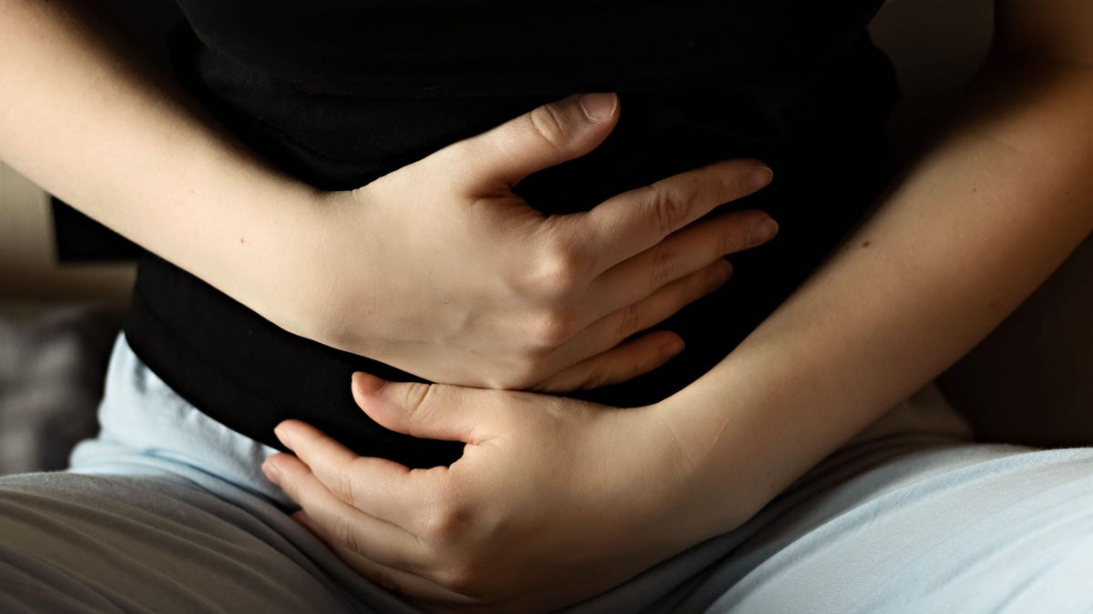 Woman holding her stomach, experiencing abdominal pain