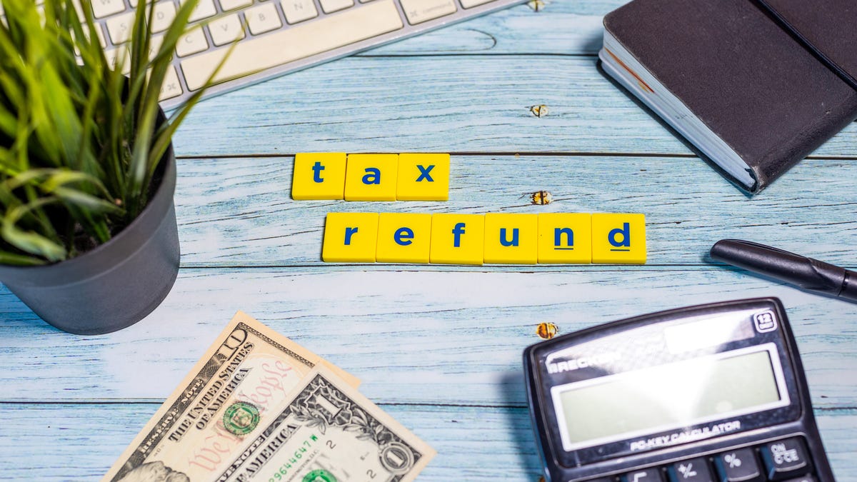 letters spelling out tax refund on a desk with items suggesting bookkeeping