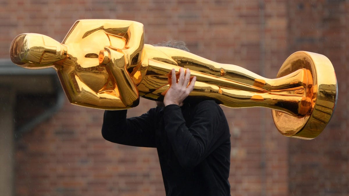 A worker carries an oversized Oscar statue over his shoulder