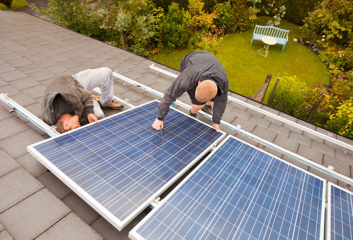 Workers putting solar panels on a roof