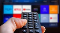 person holding remote pointing at smart tv