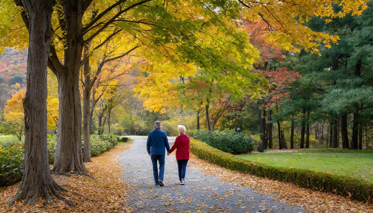 An AI-generated image of a couple strolling along a gravel path with fall foliage all around