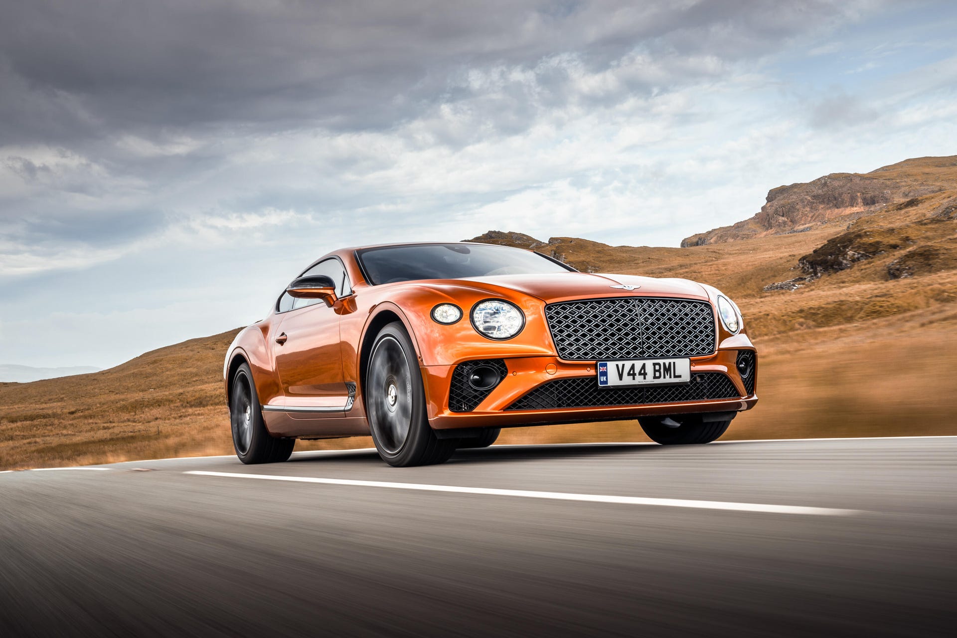 Front 3/4 view of an orange Bentley Continental GT Mulliner W12 in motion