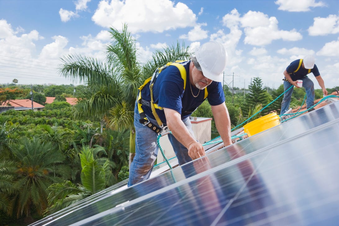 Güneş enerjisi tesisatçıları Florida'da bir çatıya paneller yerleştirdi.