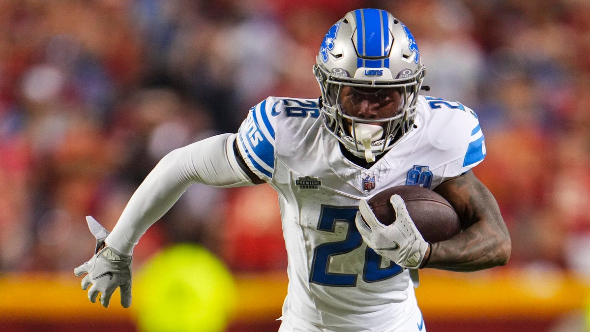 Detroit Lions running back Jahmyr Gibbs running with a ball under his left arm.