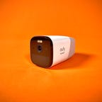 The Eufy 4G Starlight Cam against an orange background. It's a battery-powered, indoor/outdoor security camera that connects over Wi-Fi or LTE.
