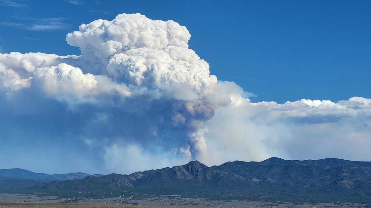 A large smoke plume rising from mountains on the horizon