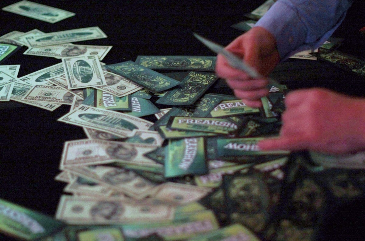 Black Hat 2010 attendees grab wads of fake money spewed out by an ATM machine hacked by Barnaby Jack.