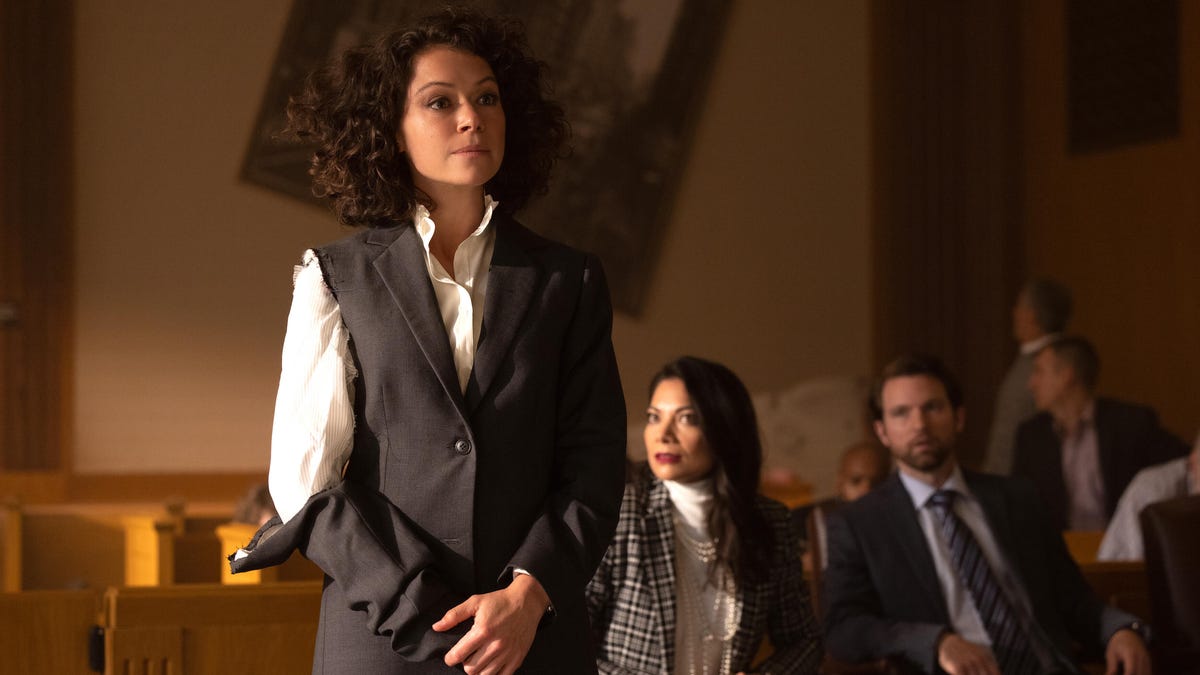A woman with a torn suit tries to look composed in a chaotic courtroom.