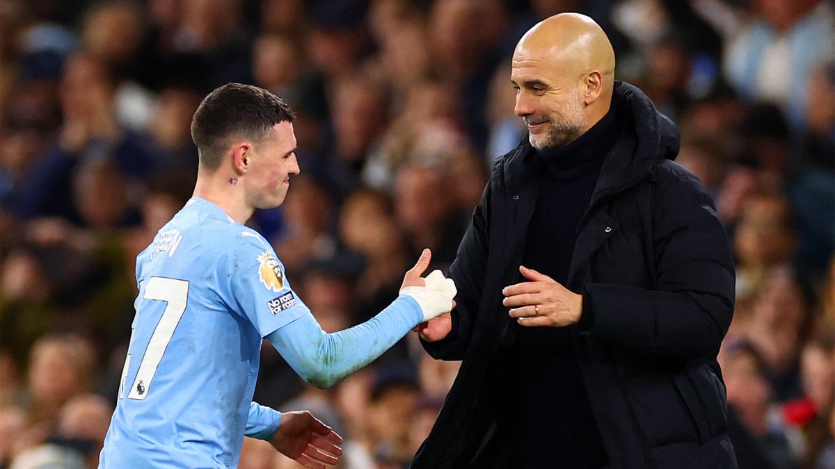 Phil Foden of Man City (left), being congratulated by manager Pep Guardiola (right).