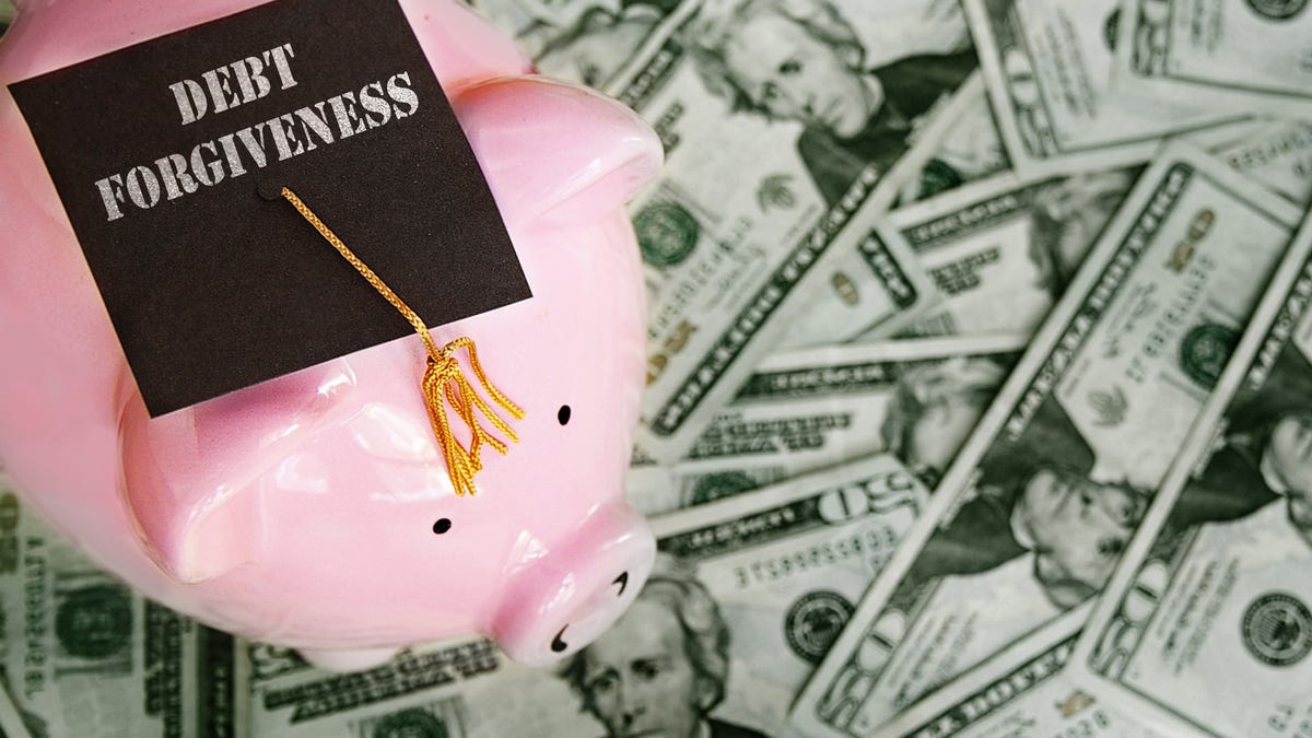 Piggy bank with mortarboard standing over pile of money.