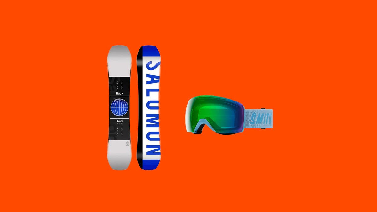 A snowboard and a pair of goggles on an orange background
