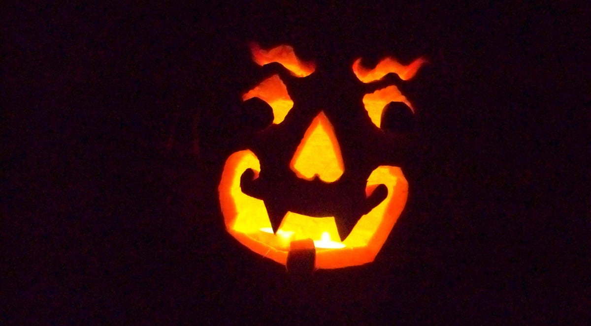 A carved pumpkin face lit from inside