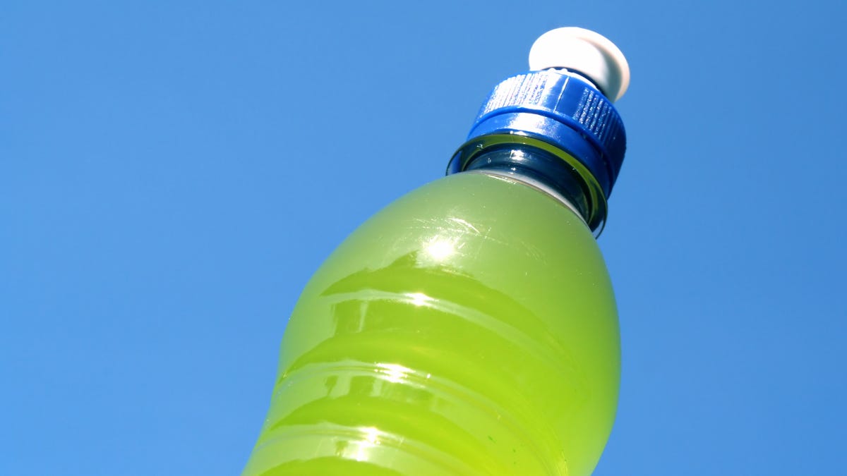 Clear water bottle filled with lime green sports drink against a blue sky
