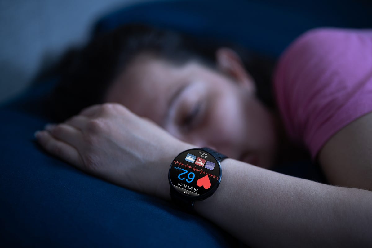 A wearable sleep tracker on a woman's wrist showing her heart rate.