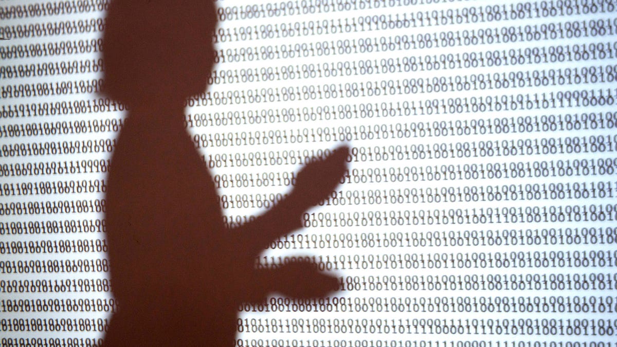 Silhouette of person in front of computer code