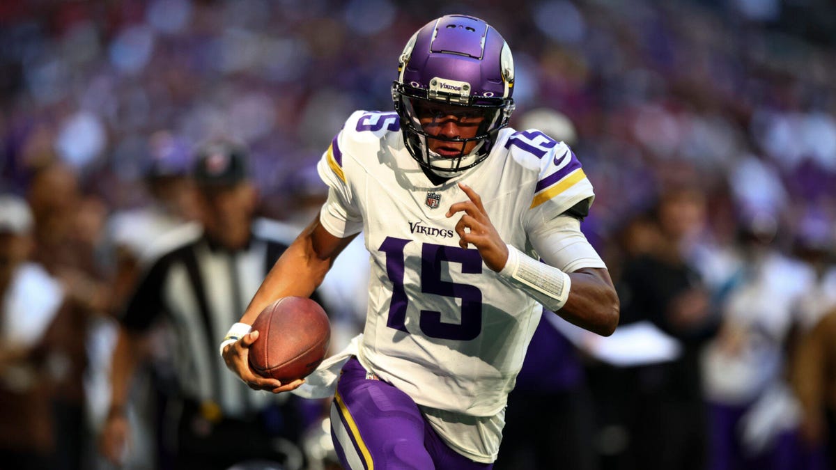 Minnesota Vikings quarterback Joshua Dobbs running towards the camera with the ball clutched under his right arm.