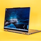 Lenovo Yoga 7i 2022 14-inch two-in-one laptop in stand mode with the display facing left on a yellow background.