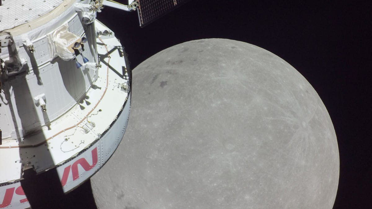Gray moon looms large as Orion spacecraft appears on the left side in a partial view.