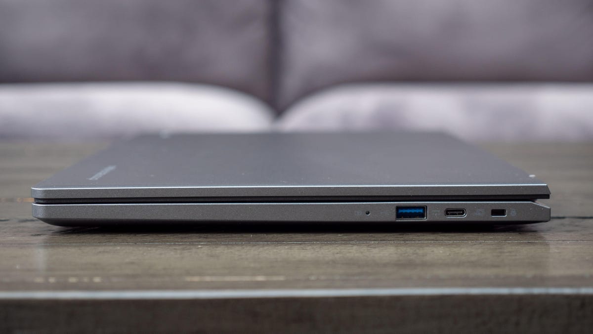 O lado direito do Acer Chromebook Plus 514 fechado sobre uma mesa de madeira em frente a um sofá cinza claro.