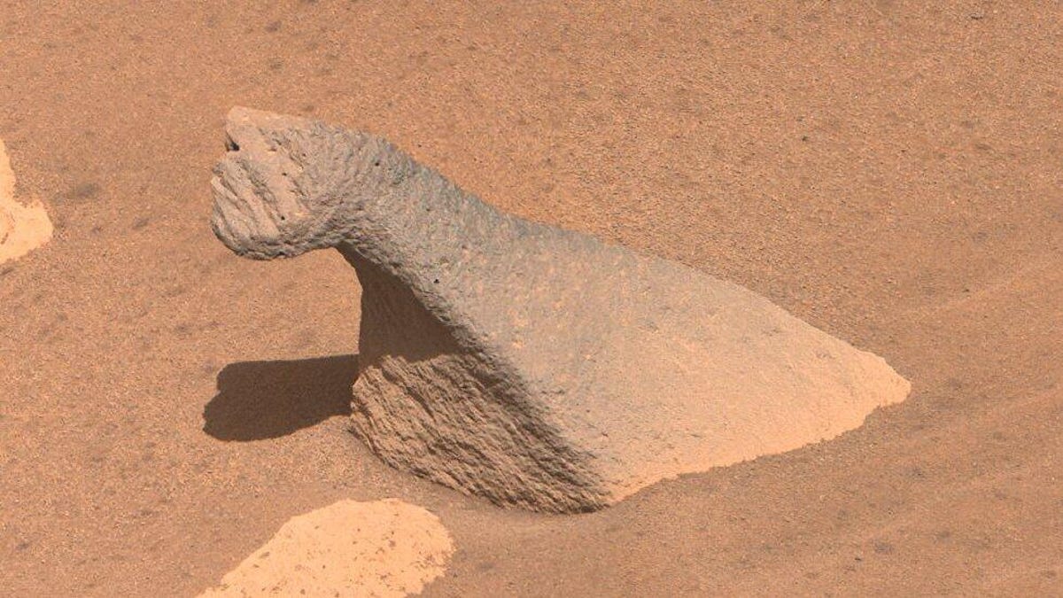 A small brachiosaurus-shaped rock extends from sandy Mars surface.
