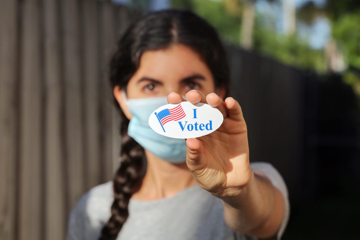 Woman holds up "I voted" sticker