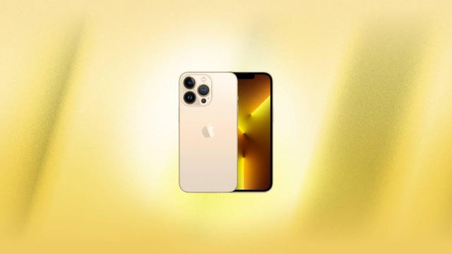 A gold iPhone 13 Pro against a yellow background.