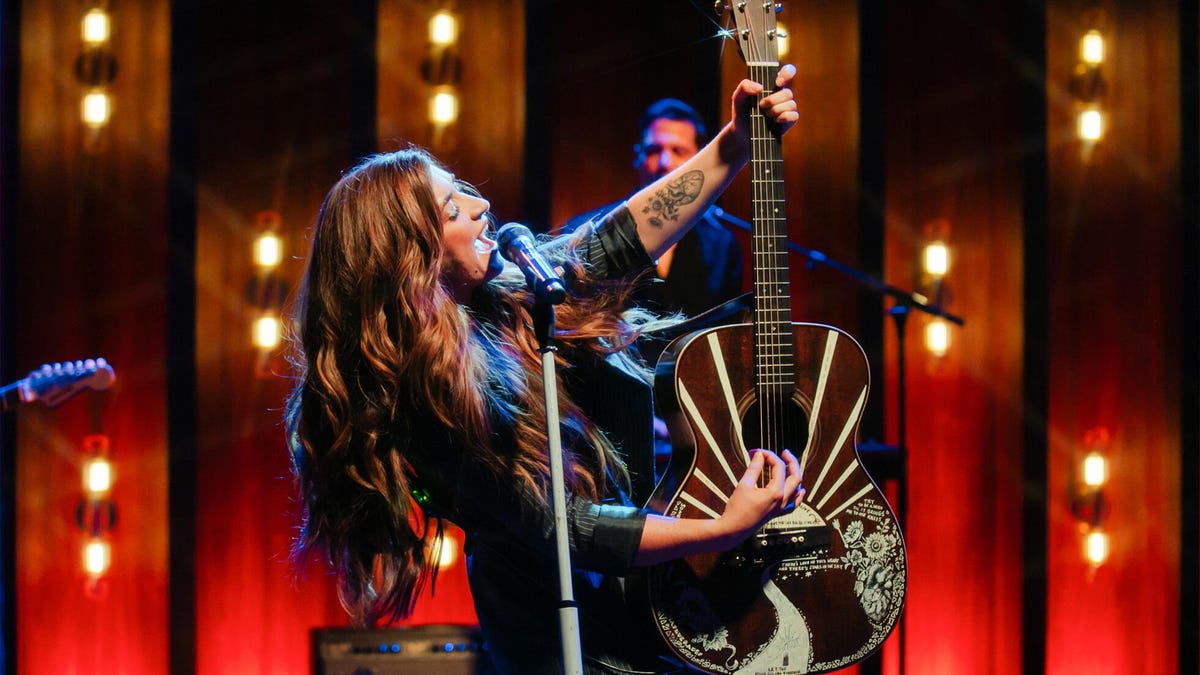 Tenille Townes singing into a mic and holding a guitar