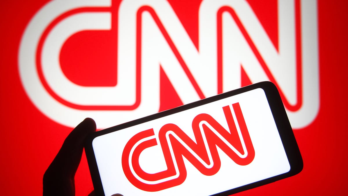 A phone with the CNN logo held in front of a larger CNN logo.
