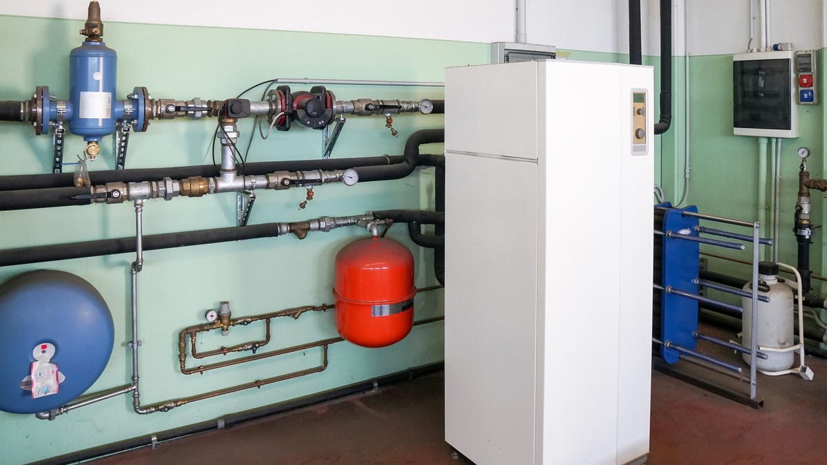 A geothermal heat pump unit in a basement surrounded by pipes.