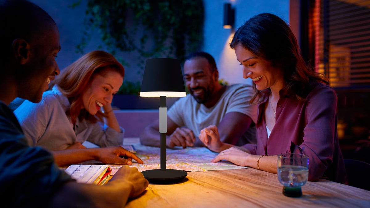four people having fun looking at something in the light of a table lamp