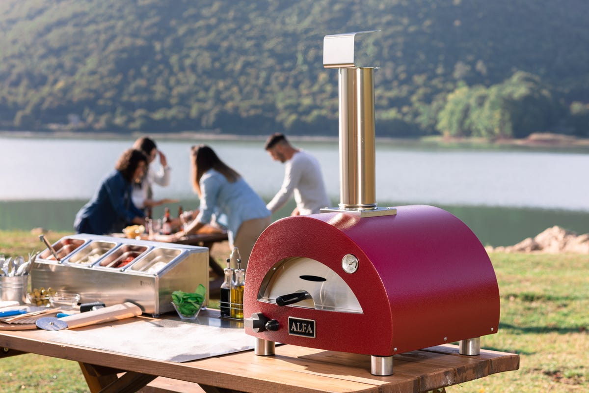 alfa pizza oven on picnic table in front of lake