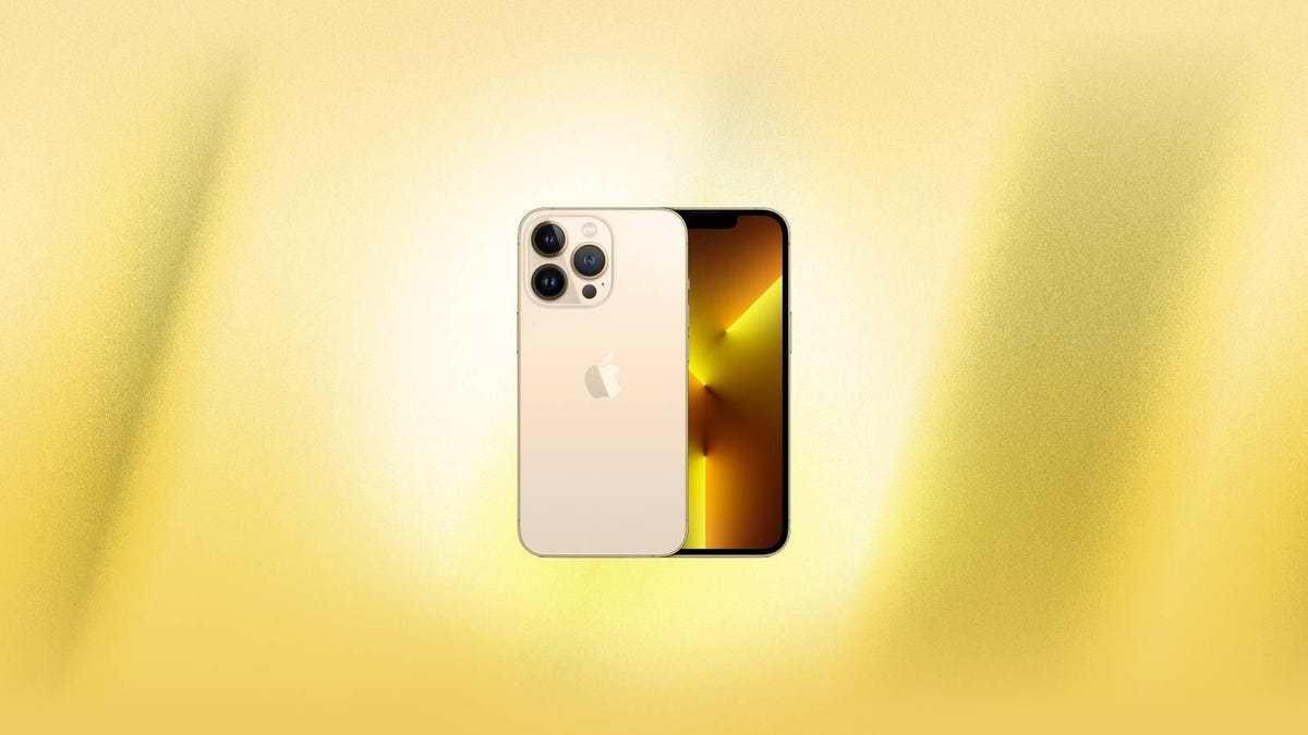 A gold iPhone 13 Pro against a yellow background.