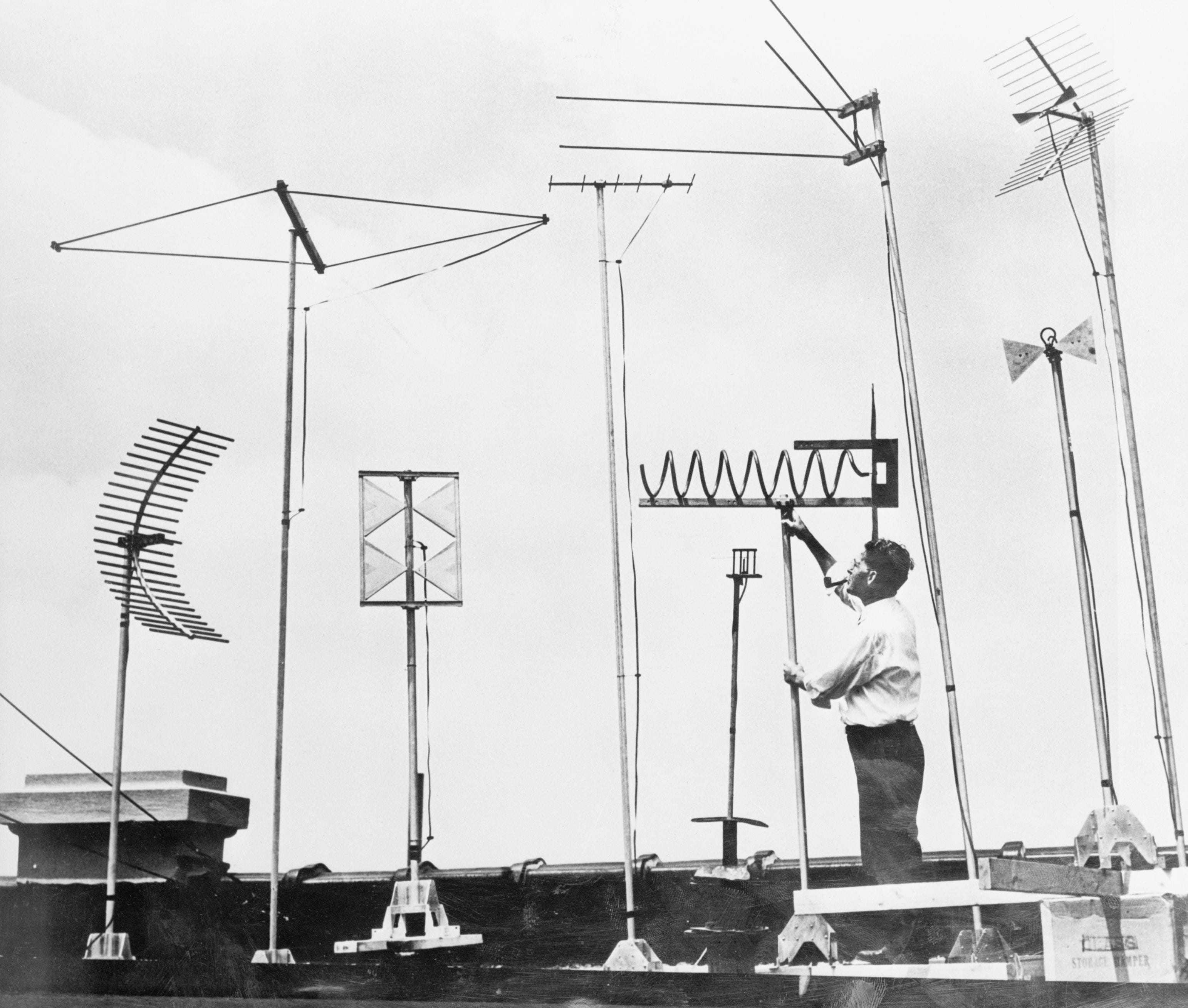 屋根のテレビ アンテナを調整する技術者