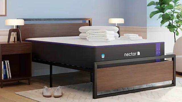 A bedroom shows a bed frame with a Nectar Premier mattress and folded bedding on top.