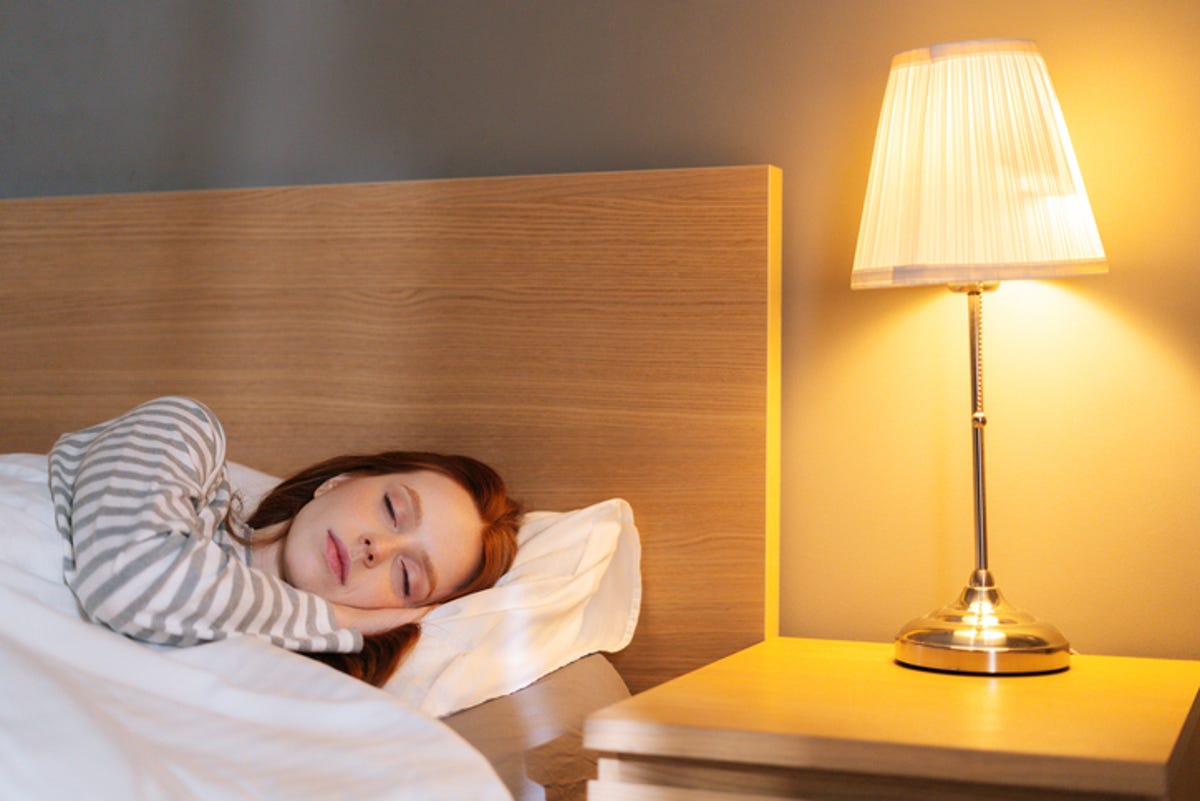 Woman asleep in bed with the bedside lamp on