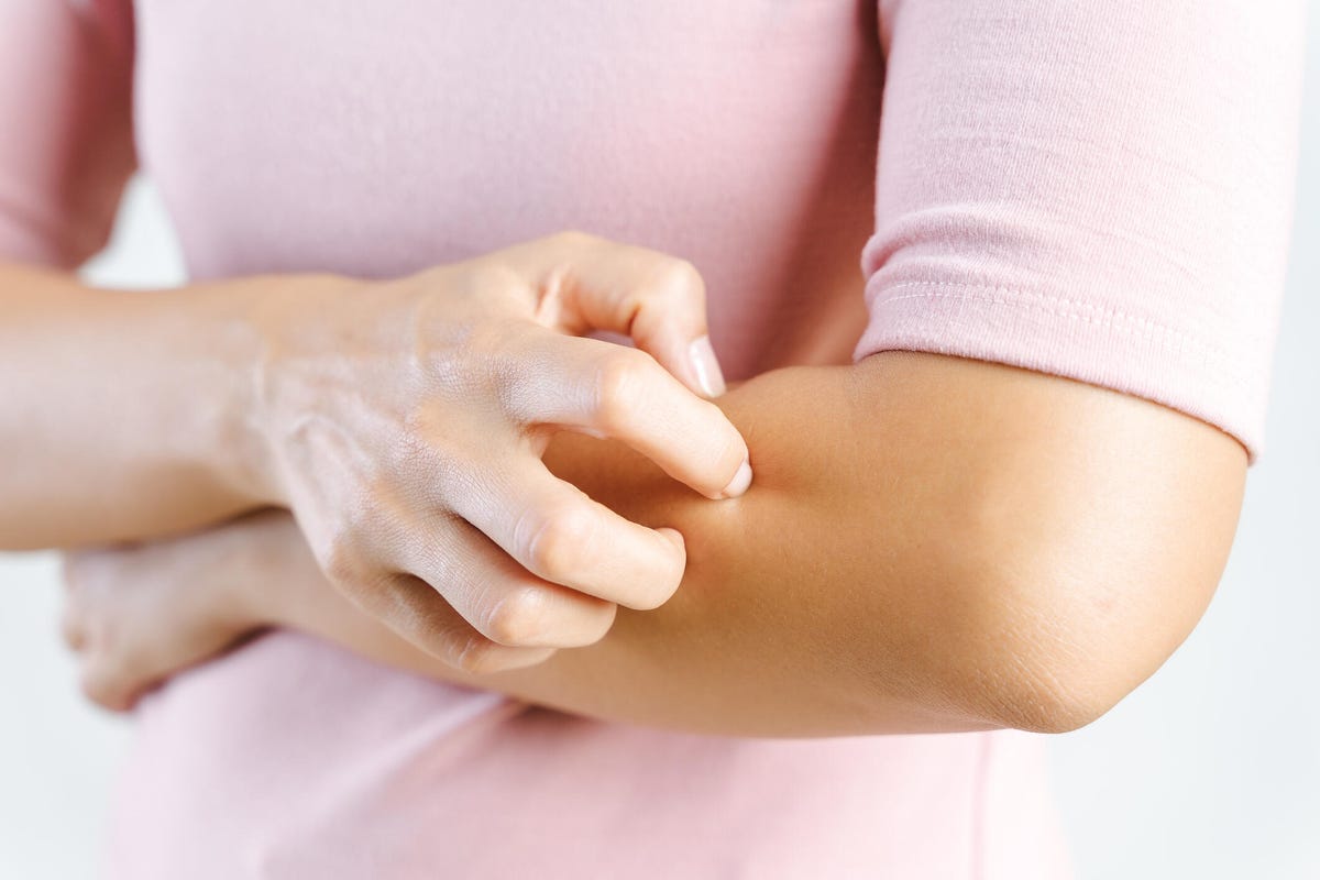 Belly of woman scratching hand against white background