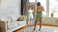 Woman standing in front of a mirror with measuring tape around her waist