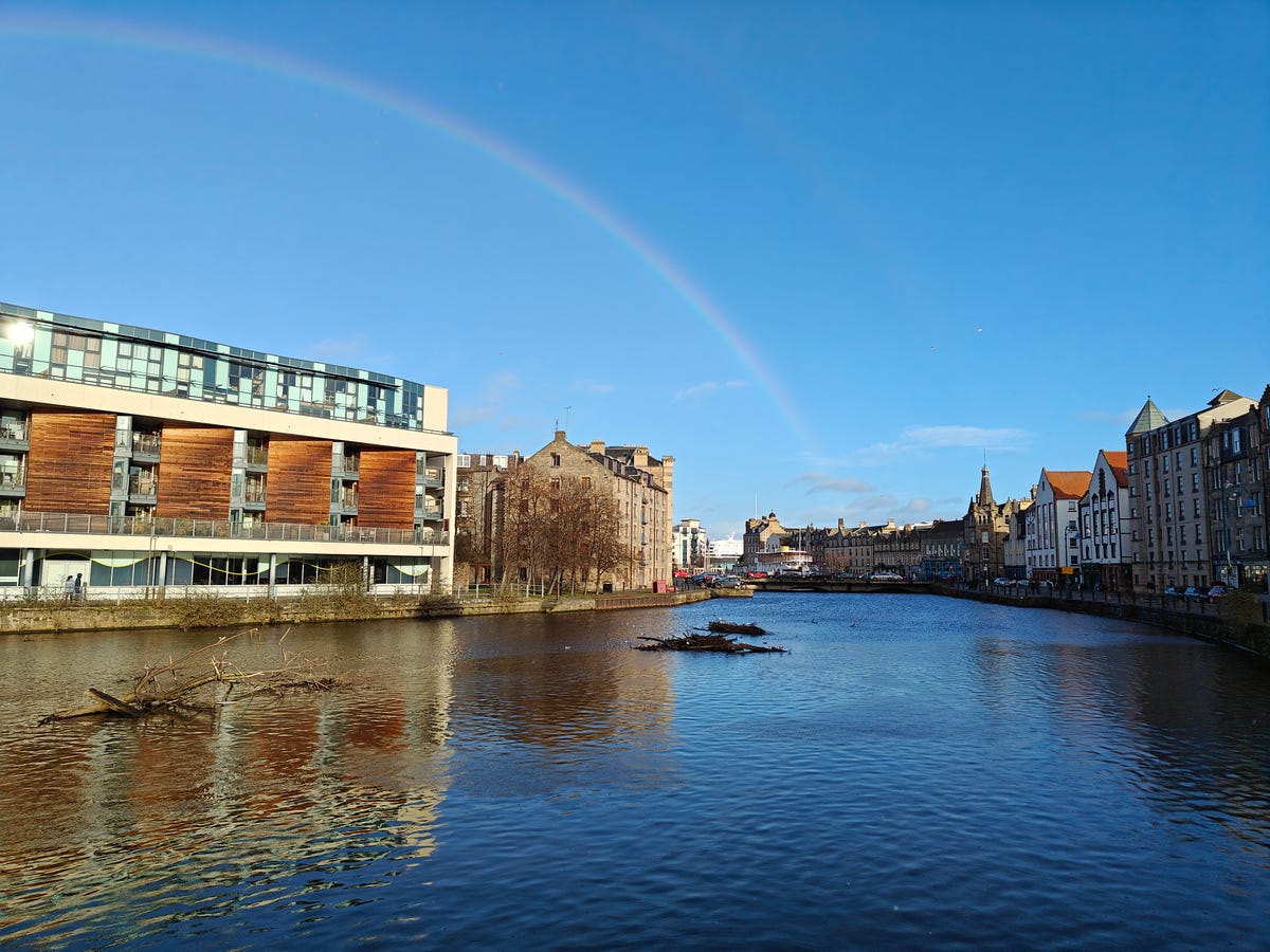 a rainbow over a building along the river