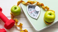 scale with apples, dumbbells and measuring tape