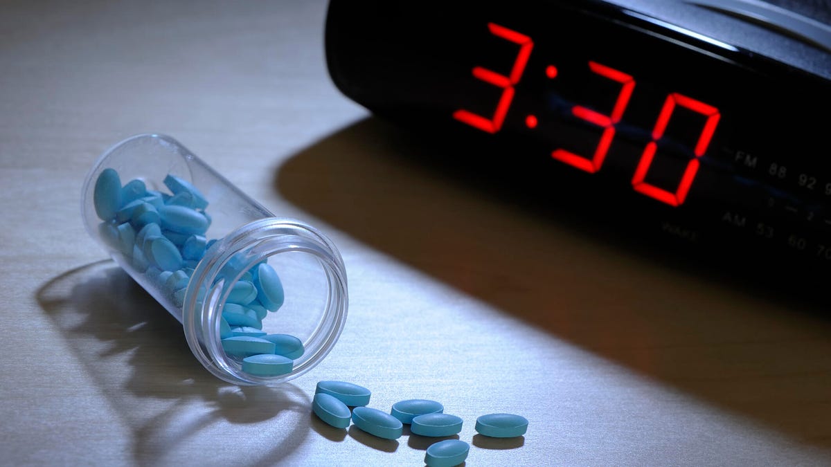 Sleeping pills next to an alarm clock