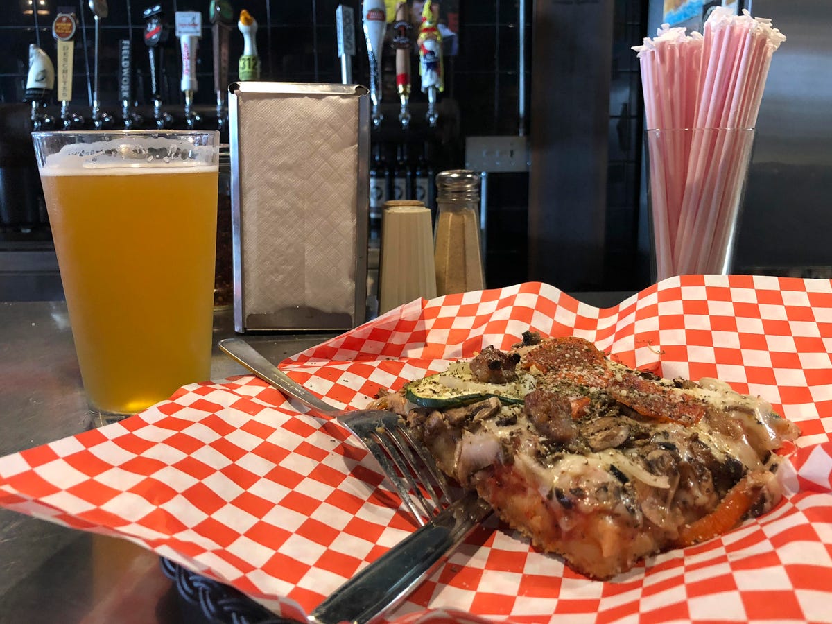 A Fieldwork Brewing Co. beer and a combo slice of pizza for lunch at Golden Boy Pizza in North Beach, San Francisco.