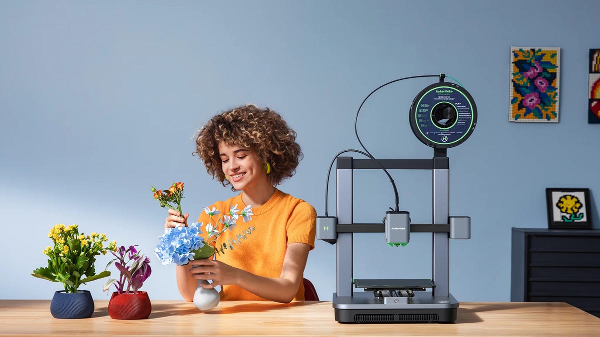 A woman arranging flowers with a silver 3D printer next to her