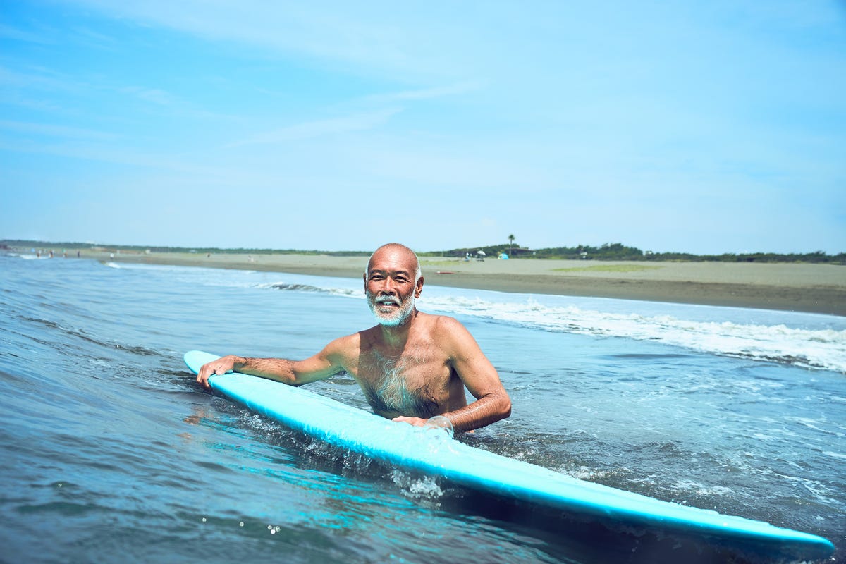 Older person in the water with a surfboard.