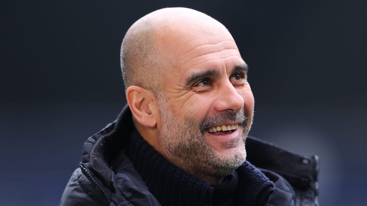 Manchester City manager Pep Guardiola laughs as he looks to the left.